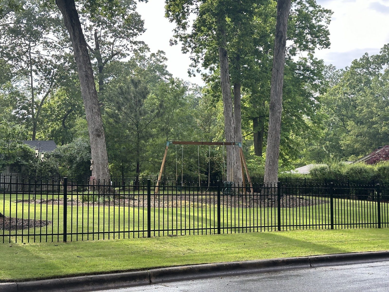 Black metal fence around a yard with a swing